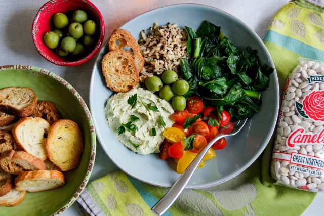 a mediterranean bowl wwith an assortment of meditteranean food in it