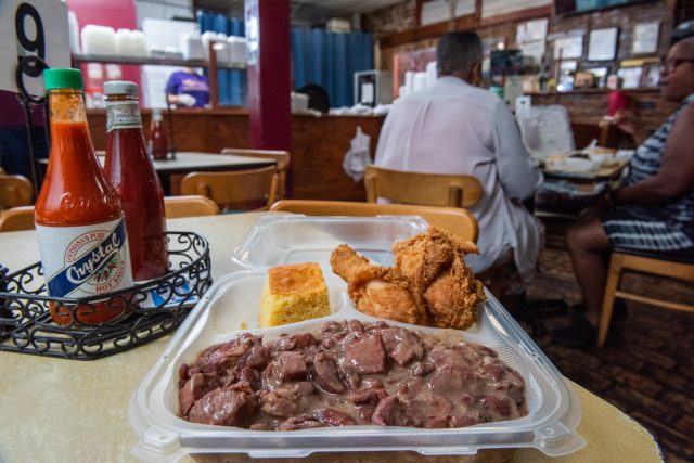 Plate of red beans, two pieces of friend chicken and a slice of cornbread.