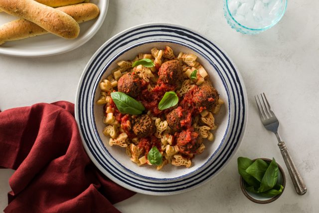 a bowl of kid friendly vegan meatballs and pasta that is crawfish shaped