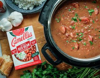 a top down view of a dutch oven full of red beans next to a box of camellia brand creole seasoning