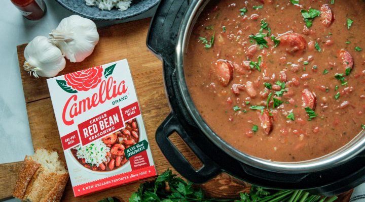 a top down view of a dutch oven full of red beans next to a box of camellia brand creole seasoning