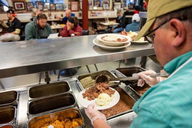 Chef serving a plate of red beans and rice at Mother's Restaurant