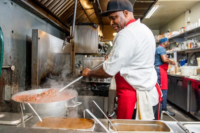 Chef stirring a giant pot of red beans 