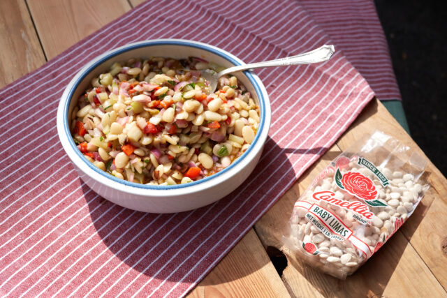 a close up of a bowl of picnic baby limas next to a package of baby lima beans