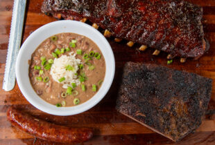 a close up of a bowl of red beans and rice next to a slab of ribs from Blue Oak BBQ Restaurant
