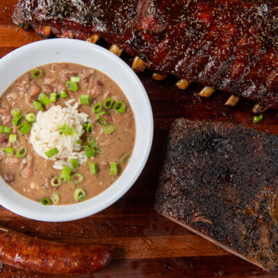 a close up of a bowl of red beans and rice next to a slab of ribs from Blue Oak BBQ Restaurant