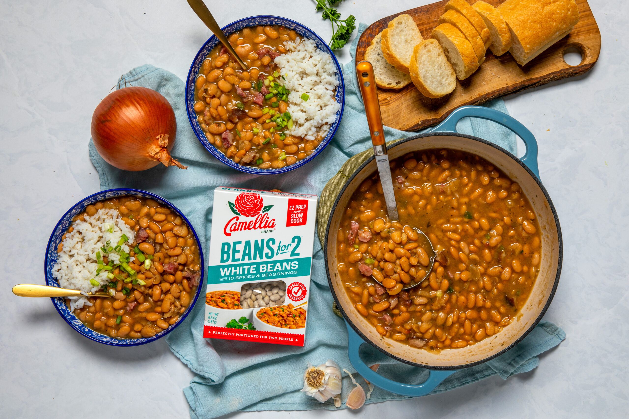 White Beans for 2 box, next to a pot of cooked white beans and two bowls of white beans and french bread
