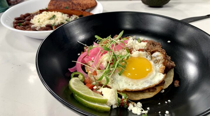 a close up of pico de gallo on a dish of red bean huuvos rancheros wwith a side of red beans and rice with sausage