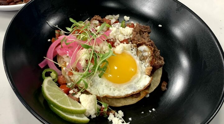 a close up of a dish of red bean huuvos rancheros wwith a side of red beans and rice with sausage