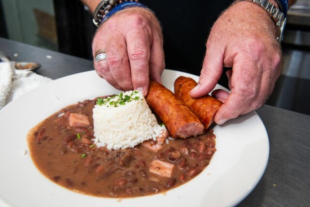 a close up of red beans and rice at kate's resturant with a side of sausage