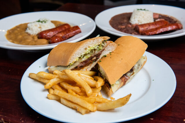 po boy on plate in front of bowls of red beans and rice at katie's restaurant in new orleans