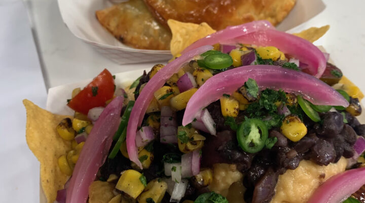 close up of pickled red onions on top of plate of nachos