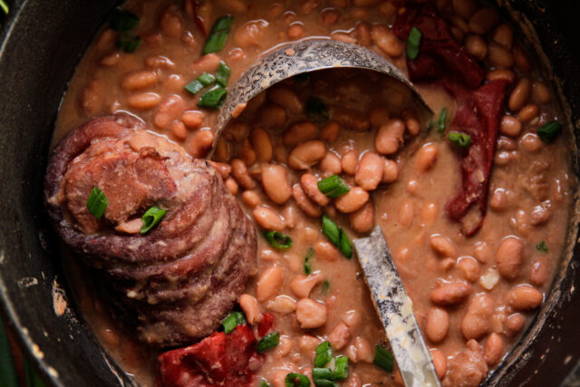 pinto beans and ham in a bot with a ladle