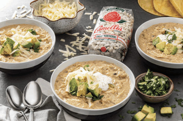 White bean and chicken chili in a white bowl next to a bag of dried beans 