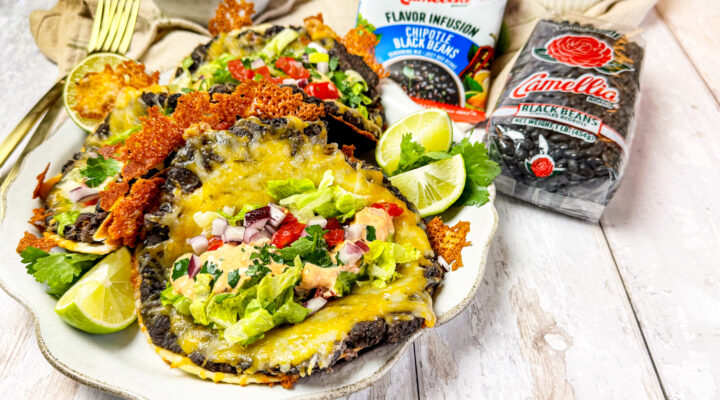 Black bean smash burger tacos on a white plate next to a bag of dried black beans and chipotle black beans flavor infusion packet