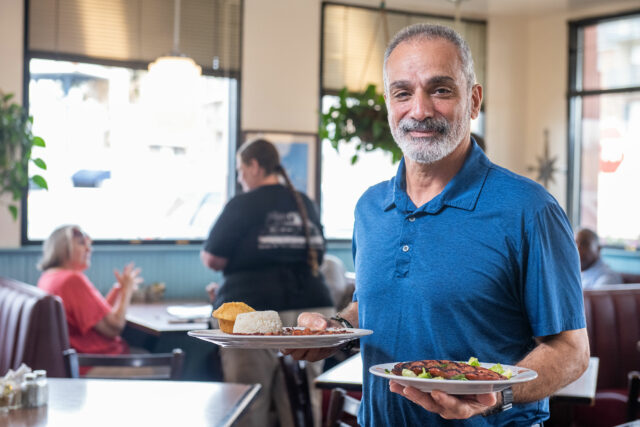 Man holding plates of red beans in restaurant