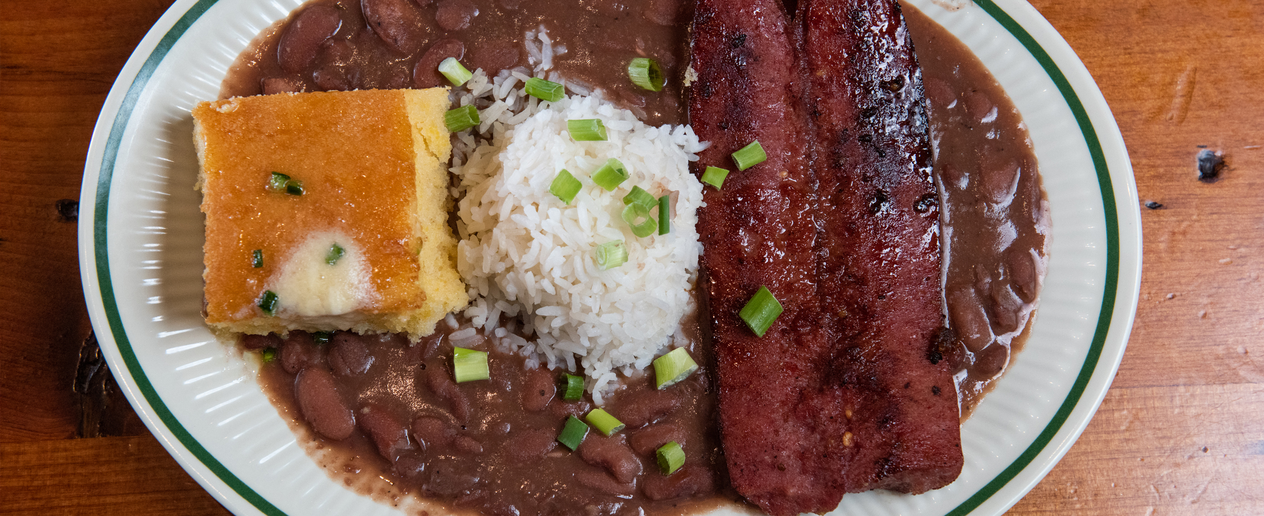 a top down view of a plate of red beans and rice with a side of cornbread